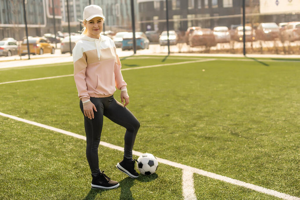 Fútbol femenino bonito. Mujer joven en ropa deportiva con una pelota de fútbol en la hierba - Foto, Imagen