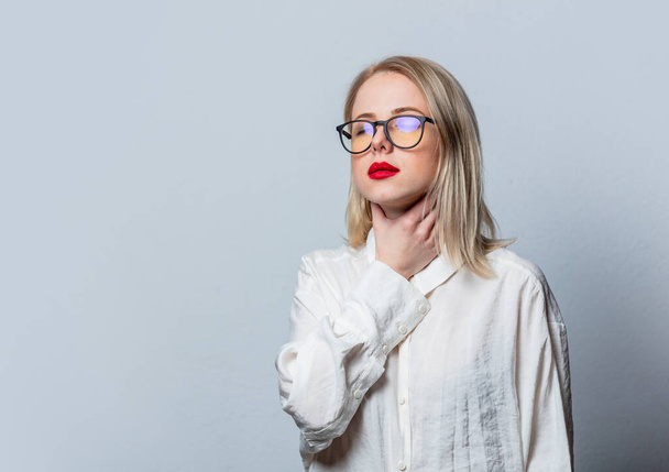 Blonde in glasses and white shirt with sore throat on white background - 写真・画像