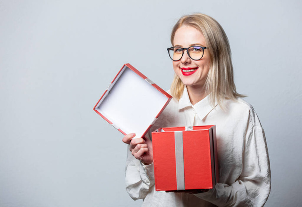 Portrait of beautiful blonde in white shirt with gift box on white background - Photo, Image
