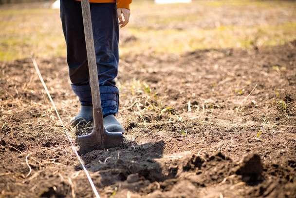 farmer man boot on spade prepare for digging. Worker loosen black dirt soil with shovel in garden at farm. griculture concept - Fotó, kép