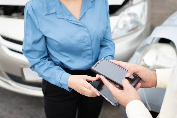 Δύο οδηγοί που χρησιμοποιούν smartphone για να ανταλλάξουν τηλέφωνα και μέσα κοινωνικής δικτύωσης μετά από αυτοκινητιστικό ατύχημα. Έννοια της ασφάλισης αξίωση για αυτοκινητιστικό ατύχημα σε απευθείας σύνδεση μετά την αποστολή φωτογραφιών και αποδεικτικών στοιχείων στην ασφαλιστική εταιρεία - Φωτογραφία, εικόνα