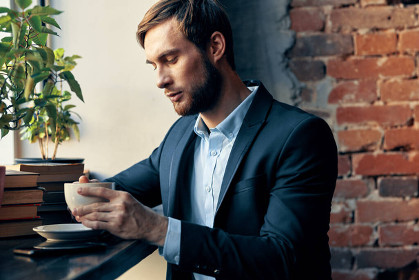 чоловік у костюмі сидить у кафе з чашкою кавового дозвілля Професіонал
 - Фото, зображення