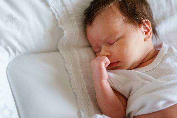 Close up sul neonato di due settimane caucasico bambino che dorme a letto a casa - carino bambina dormire tranquillamente vista dall'alto verso il basso - Foto, immagini