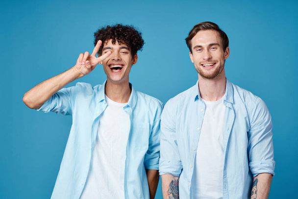 Männer in identischen Hemden und weißen T-Shirts auf blauem Hintergrund unterhielten sich mit Freunden. - Foto, Bild