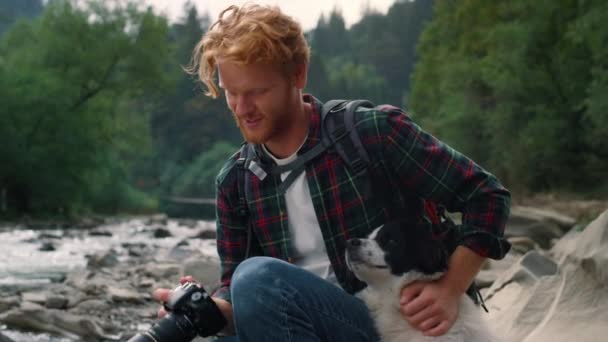 Glücklicher Typ, der Hund im Freien streichelt. Lächelnder Wanderer genießt Naturlandschaft - Filmmaterial, Video