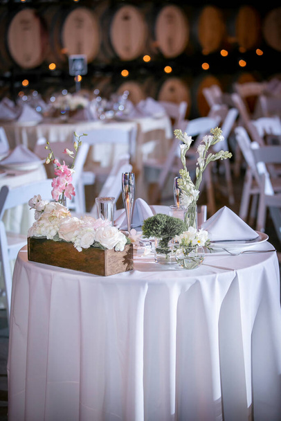 Elegantly set tables for an evening dinner wedding ceremony with candles and flowers as center pieces - Photo, Image