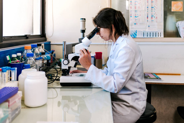 Zdjęcie kobiety naukowiec przy użyciu mikroskopii w jej laboratorium. - Zdjęcie, obraz