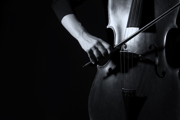 Hermosa mujer sosteniendo un violonchelo con luz selectiva y d negro
 - Foto, imagen