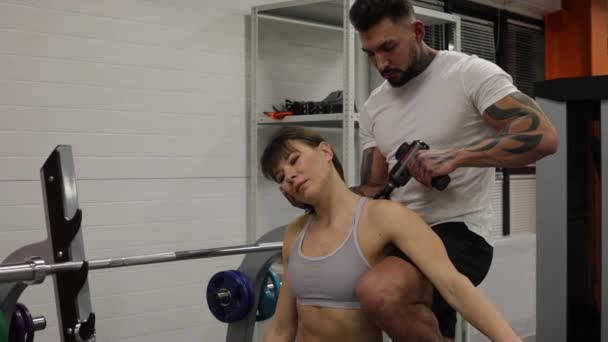 Προσωπικός γυμναστής που τεντώνει τα πόδια της αθλήτριας στο γυμναστήριο - Πλάνα, βίντεο