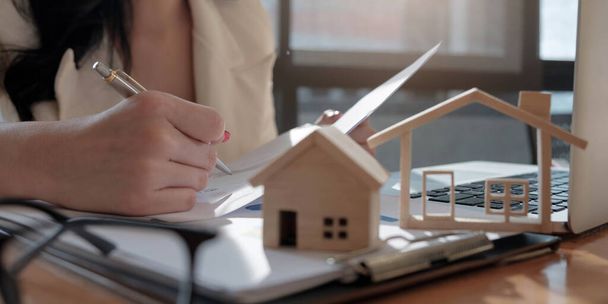 agente imobiliário auxiliando cliente a assinar contrato de papel na mesa com modelo de casa - Foto, Imagem
