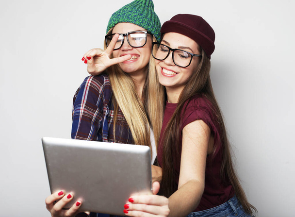 two girls friends taking selfie with digital tablet over grey background - Zdjęcie, obraz