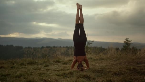 Donna atletica che fa posa poggiatesta yoga. Fitness ragazza in piedi sulla testa all'aperto - Filmati, video