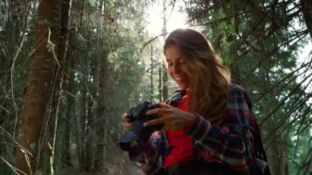 Chica con cámara fotográfica de pie en el bosque. mujer celebración profesional cámara  - Imágenes, Vídeo