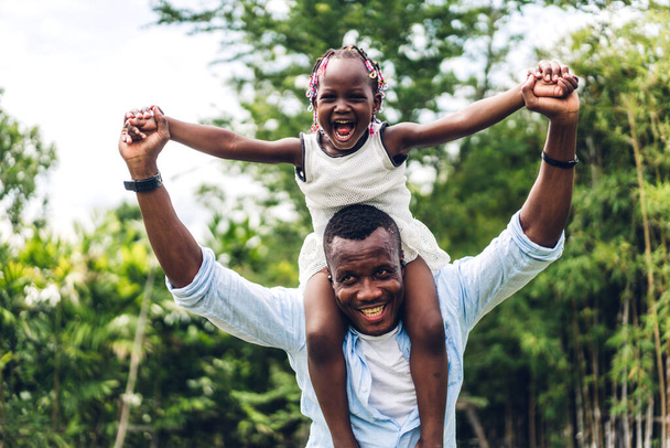 Portrait of enjoy happy love black family african american father carrying daughter little african girl child smiling and having fun moments good time in summer park at home - Foto, imagen
