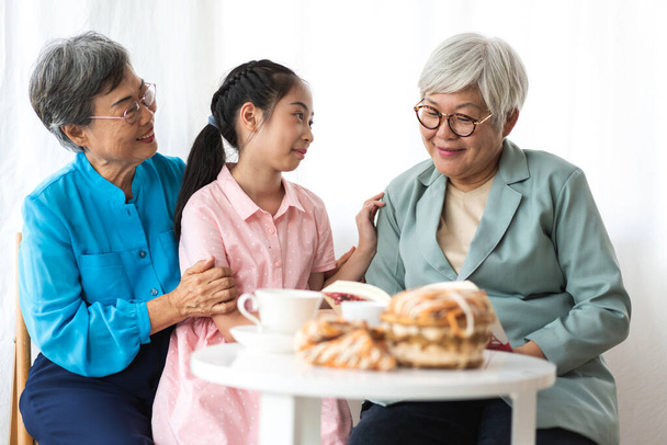 Portrait of happy asian grandmother and little asian cute girl enjoy relax in home.Young girl with their laughing grandparents smiling together.Family and togetherness - Photo, Image