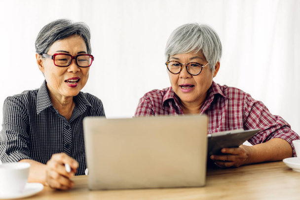Retrato de dois amigos idosos adultos felizes mulheres asiáticas sorrindo e trabalhando com computador portátil em casa.Conceito de aposentadoria - Foto, Imagem