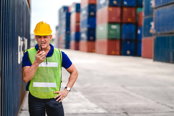 Professional engineer container cargo foreman in helmets working standing and using walkie talkie checking stock into container for loading.logistic and business export - Fotó, kép
