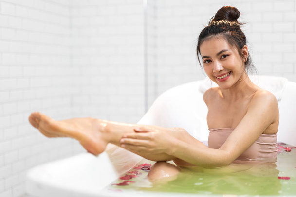 Πορτρέτο του χαμογελαστού ευτυχισμένη όμορφη ασιατική γυναίκα καθαρό φρέσκο υγιές λευκό δέρμα θεραπεία spa απολαύσετε χαλαρωτική λήψη ντους και μπάνιο με αφρόλουτρο spa στην μπανιέρα στο μπάνιο - Φωτογραφία, εικόνα