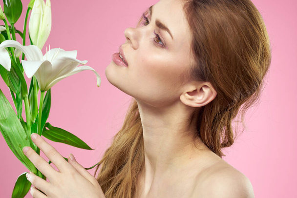 Portrait of a beautiful woman with white flowers in her hands on a pink background Copy Space cropped view - 写真・画像