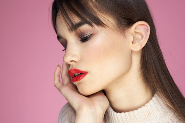 Mooie brunette in een witte trui rode lippen aantrekkelijke look roze achtergrond - Foto, afbeelding