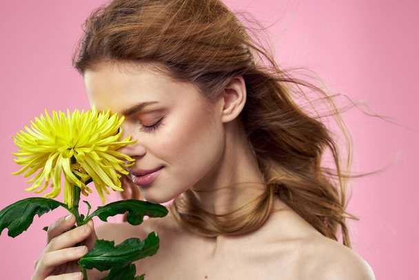 Portrait of a woman with yellow flowers on a pink background Makeup on the face - Photo, Image