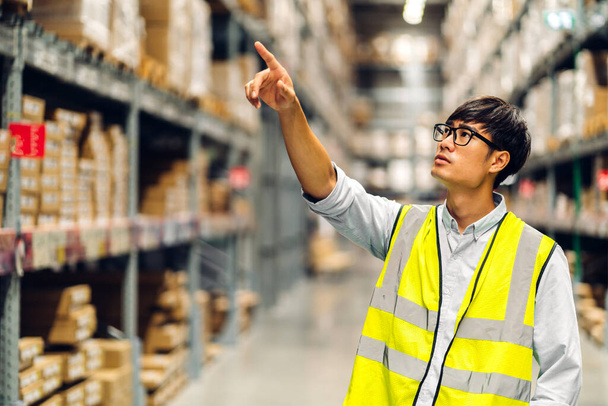 Portrait of smiling asian engineer man order details checking goods and supplies on shelves with goods background in warehouse.logistic and business export - Foto, afbeelding