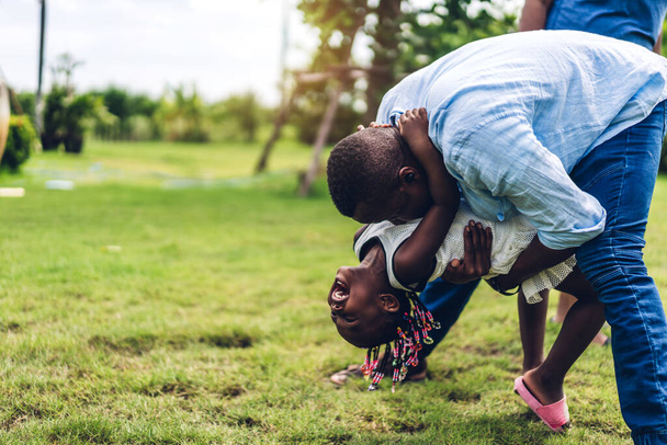 Πορτρέτο του απολαύσετε ευτυχισμένη αγάπη μαύρο οικογένεια αφροαμερικανός πατέρας και η μητέρα με το μικρό κορίτσι της Αφρικής χαμογελώντας και να παίξουν διασκεδάζοντας στιγμές καλή στιγμή στο πάρκο καλοκαίρι στο σπίτι - Φωτογραφία, εικόνα