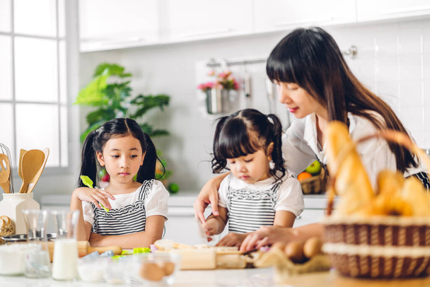 Porträt genießen glückliche Liebe asiatische Familienmutter und kleines Kleinkind asiatische Mädchen Tochter Kind Spaß beim gemeinsamen Kochen mit Backen Plätzchen und Kuchen Zutat auf dem Tisch in der Küche - Foto, Bild