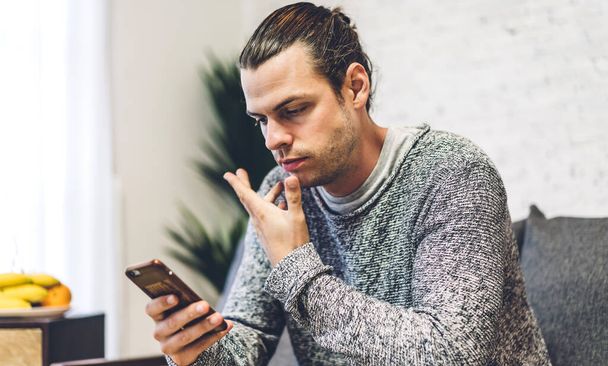 Handsome hipster man relaxing using digital smartphone with coffee and looking at screen typing message at table in cafe and restaurant,playing game online and social media - 写真・画像