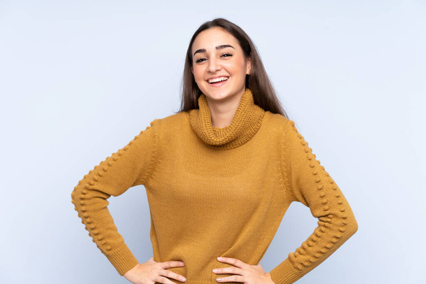 Fiatal fehér nő elszigetelt kék háttér pózol karokkal csípő és mosolygós - Fotó, kép