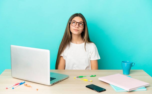 青い背景の上にノートパソコンを持つテーブルの少女と検索アップ - 写真・画像