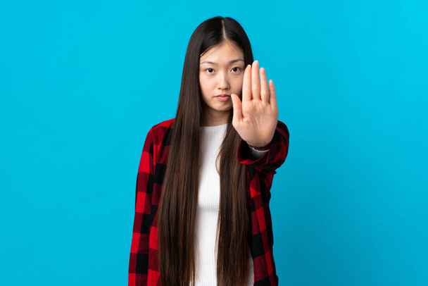 Молодая китаянка на изолированном синем фоне делает остановку жест - Фото, изображение