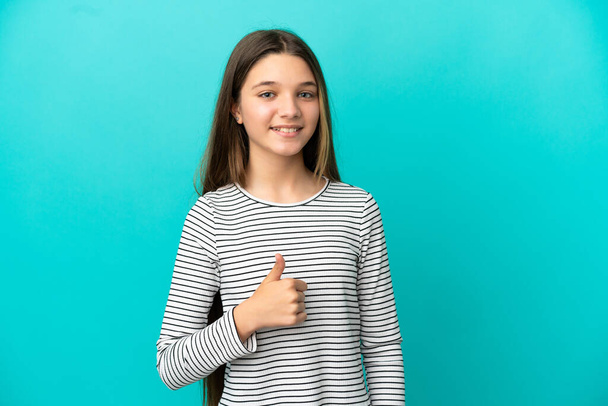 Malá dívka přes izolované modré pozadí dává palce nahoru gesto - Fotografie, Obrázek