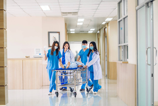 Groep van professionele arts team en assistent met stethoscoop in uniform brengen ernstig gewonde patiënt naar operatiekamer spoedeisende hulp in het ziekenhuis.gezondheidszorg concept - Foto, afbeelding