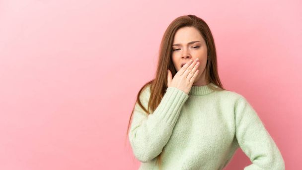 Adolescente chica sobre aislado rosa fondo bostezando y cubriendo amplia boca abierta con la mano - Foto, Imagen