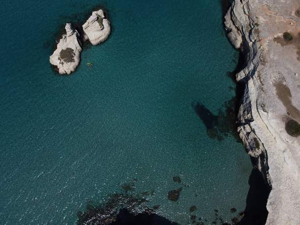 An aerial top view of mesmerizing ocean waters separated by coastal rocks - Photo, Image