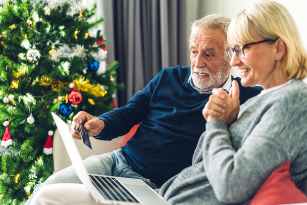 Seniorenpaar Familie mit viel Spaß mit Laptop-Computer zusammen. Glückliche ältere Männer und Frauen checken soziale Medien und lesen Nachrichten oder online einkaufen, während sie zu Hause auf dem Sofa sitzen - Foto, Bild