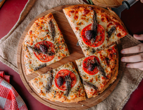pizza z sardeli, sera i pomidorów w czerwonym stole - Zdjęcie, obraz