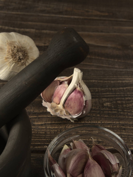 A mortar and pestle with garlic on a wooden table - Valokuva, kuva