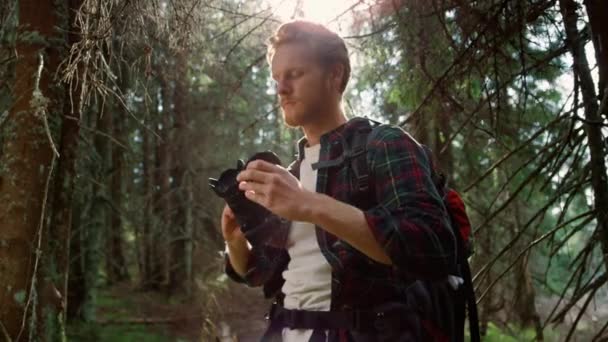 Φωτογράφος με φωτογραφική μηχανή στέκεται στο δάσος. Πεζοπόρος τραβάει φωτογραφίες στην κάμερα - Πλάνα, βίντεο