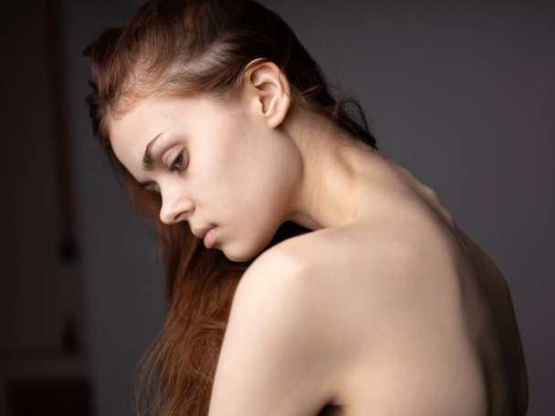 Mujer sexy con una espalda desnuda en un fondo gris pelo rojo vista posterior - Foto, Imagen