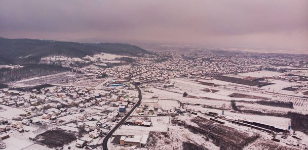 Panoramiczne ujęcie zaśnieżonej wioski pełnej małych domków, otoczonej wzgórzami - Zdjęcie, obraz