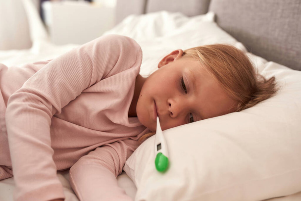 A picture of a girl lying in the bad with high fever cropped - Fotoğraf, Görsel