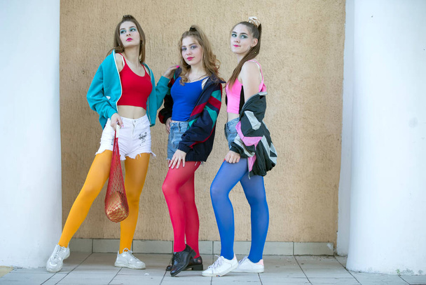 Drie mooie meisjes gekleed in de stijl van de jaren negentig poseren voor de camera. - Foto, afbeelding