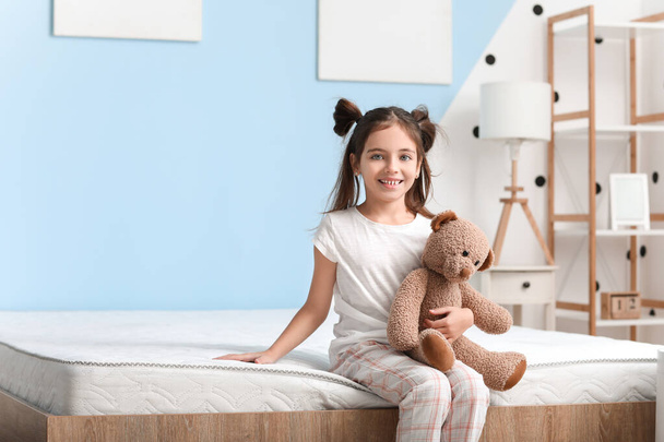 Morning of little girl sitting on bed with comfortable mattress - Foto, imagen