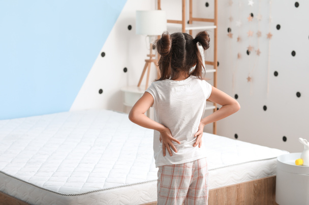 Little girl suffering from back pain in morning because of uncomfortable mattress - Foto, Imagem