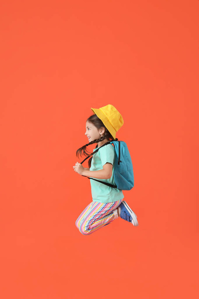 Jumping little girl with backpack on color background - 写真・画像