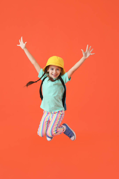 Jumping little girl with backpack on color background - 写真・画像