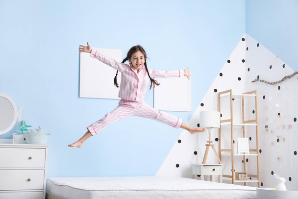 Grappig klein meisje springen op bed - Foto, afbeelding