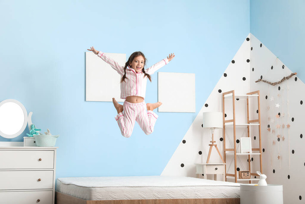 Funny little girl jumping on bed - 写真・画像